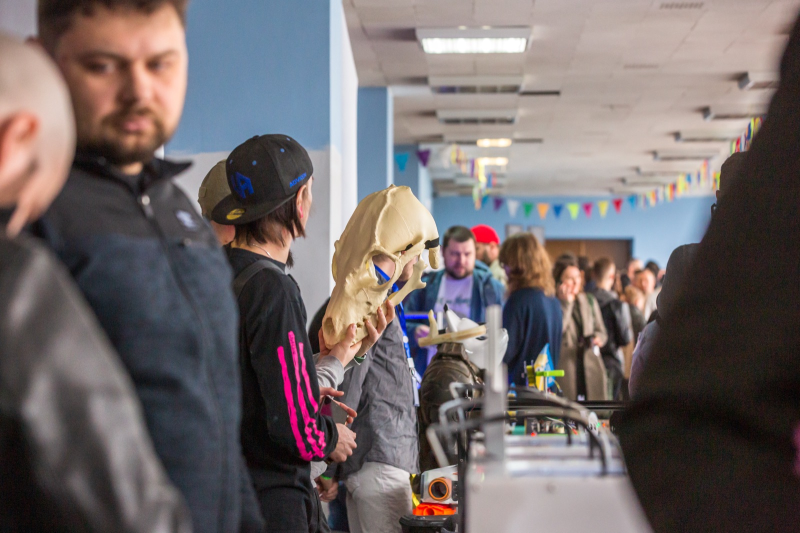 Відвідувачі біля стендів фестивалю, гість роздивляється надрукований череп